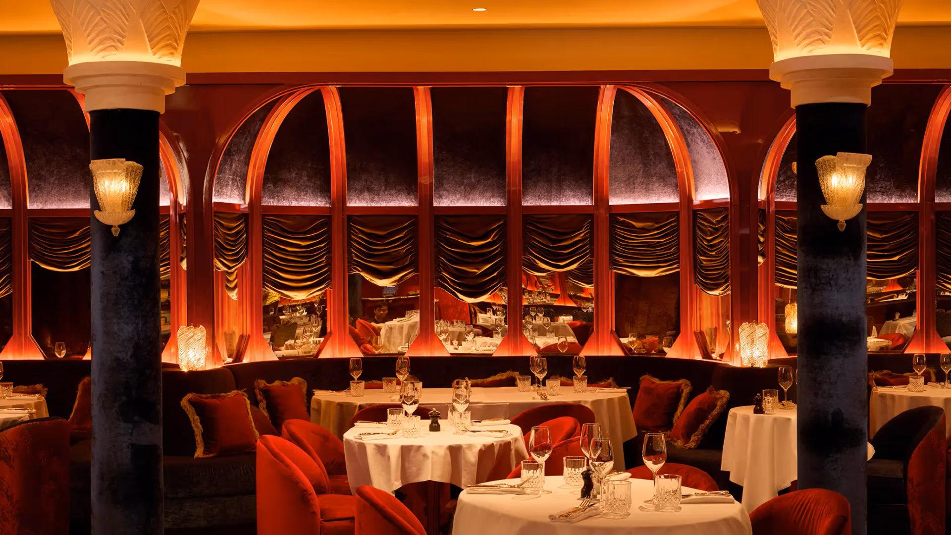 Restaurant élégant avec des tables dressées, des sièges rouges et des arches décoratives éclairées